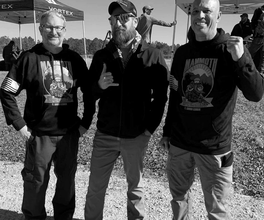Three competitors together at a long-range shooting competition.