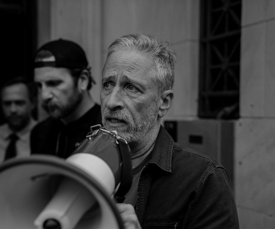 Advocates with a megaphone addressing a crowd outside a government building.