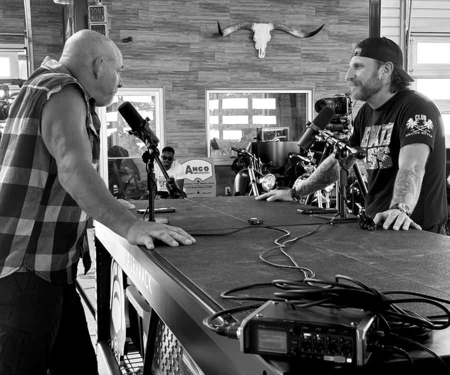 Two men recording a podcast across a studio table.